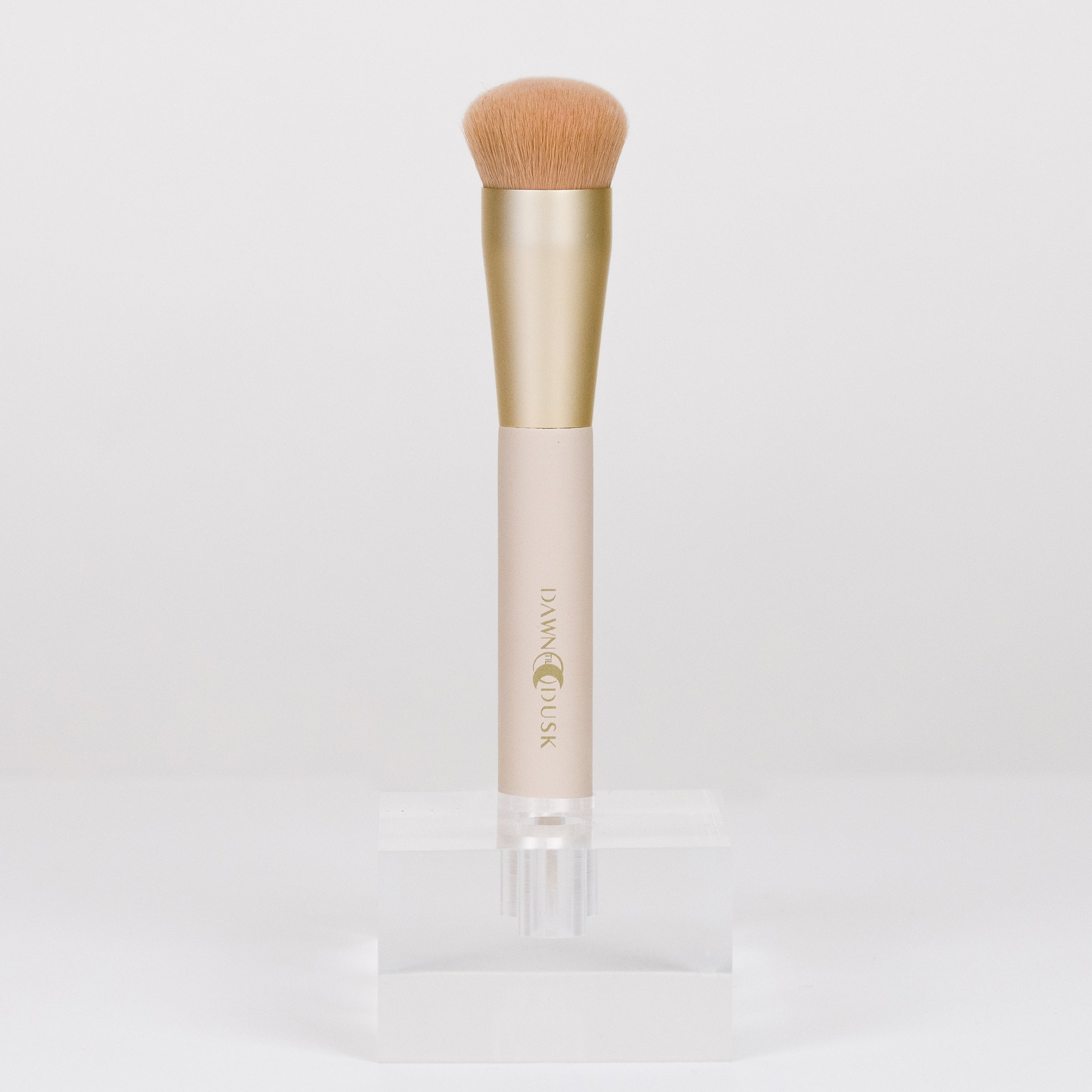 Makeup brush with a gold and beige handle on a white background