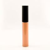 A single tube of liquid concealer or foundation standing upright on a seamless white background. The tube is a warm peach-beige shade with a glossy black cap.