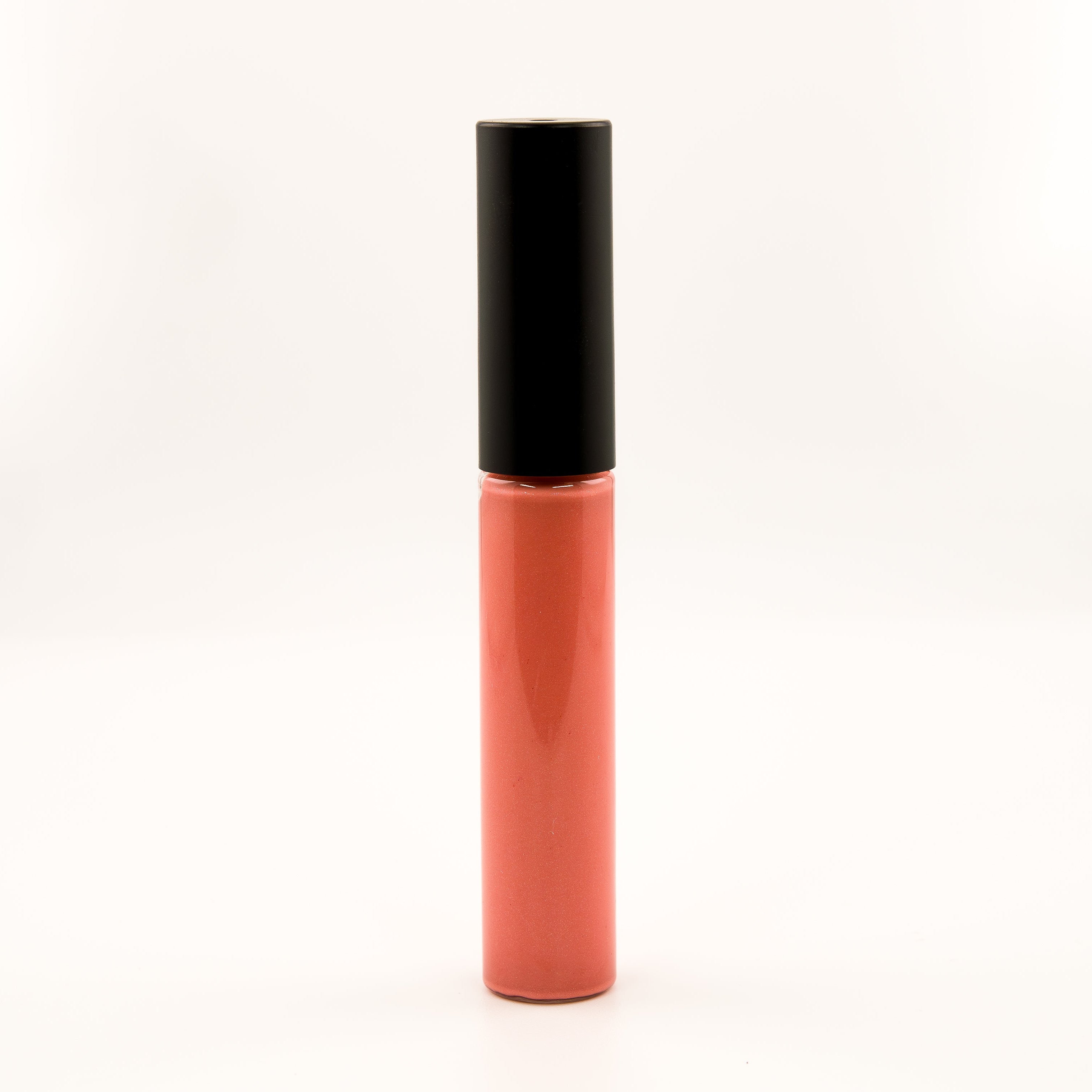 A single tube of liquid lipstick or lip gloss standing upright on a plain white background. The lower portion is a glossy coral-pink shade, and the cap is matte black.