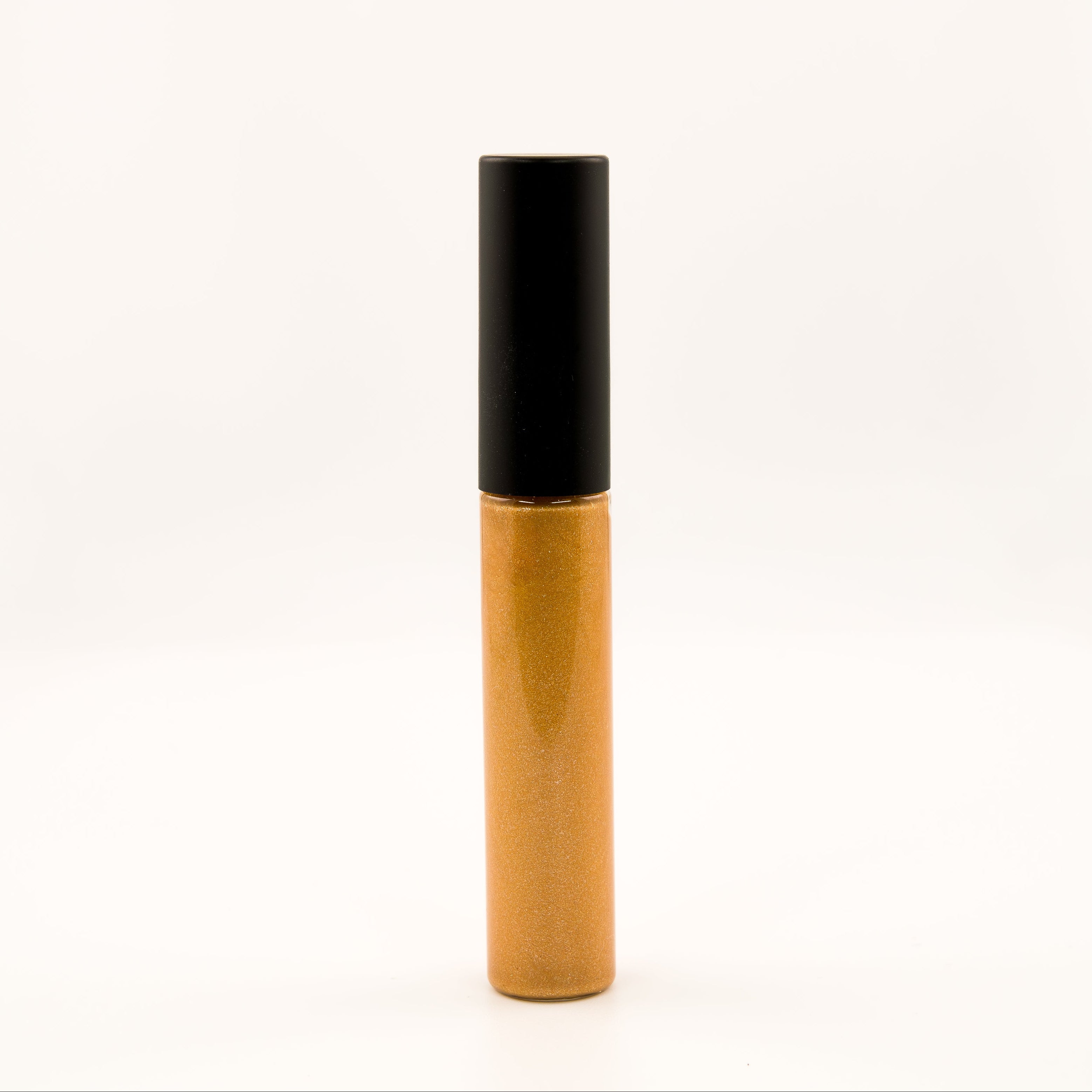 A single cosmetic tube, likely a liquid concealer or lip gloss, standing upright on a seamless white background. The tube has a glossy metallic gold body and a matte black cap.