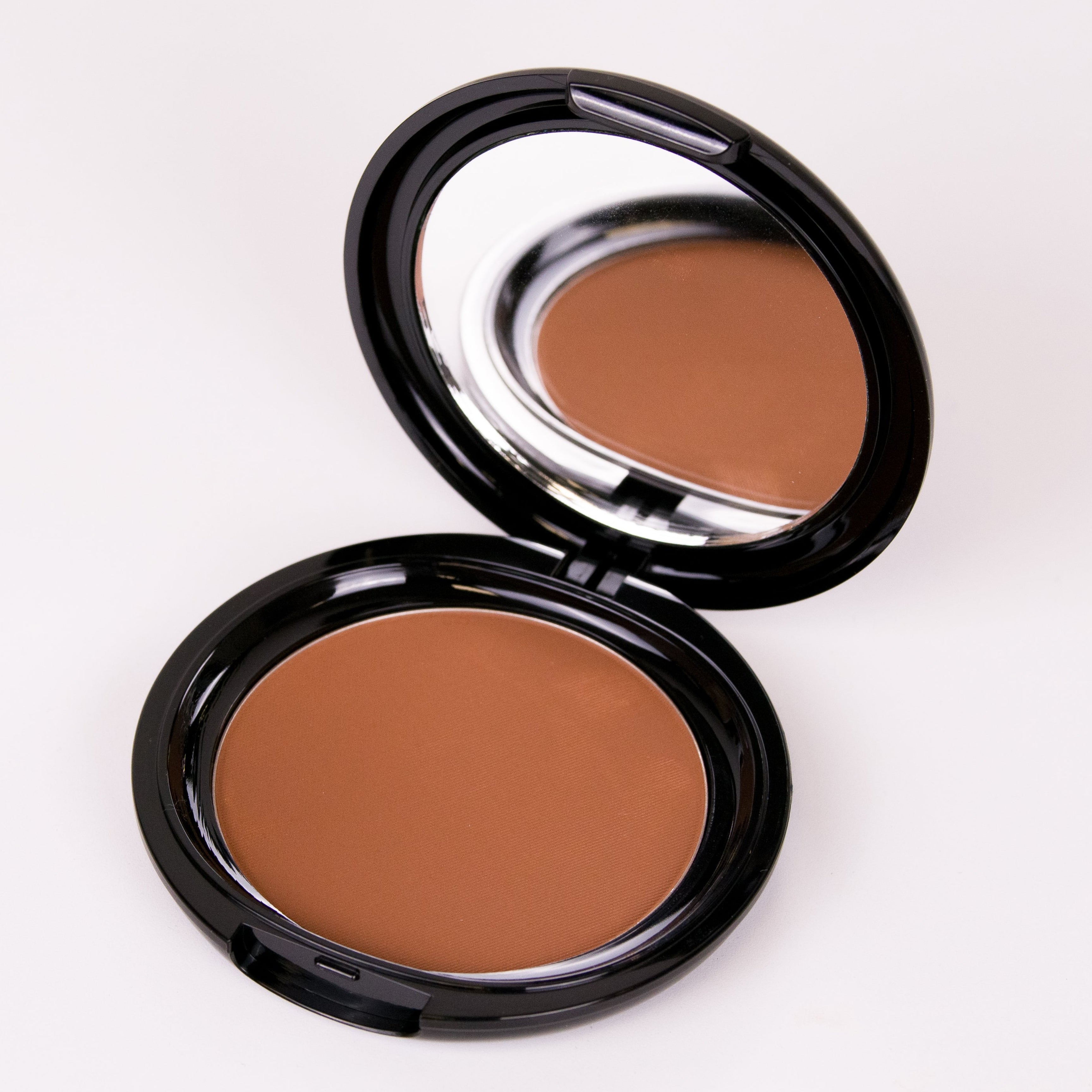 Compact brown powder in an open black case on a white background