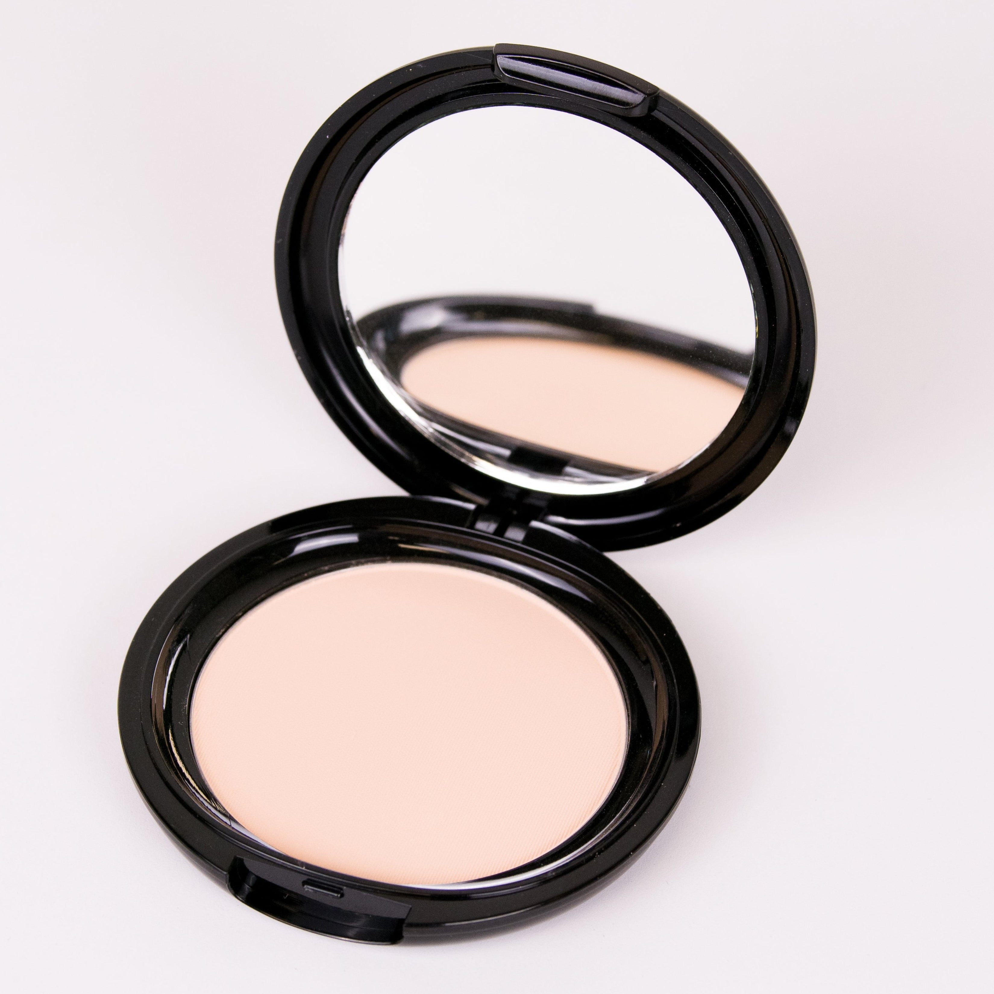 Compact powder in a black case on a white background
