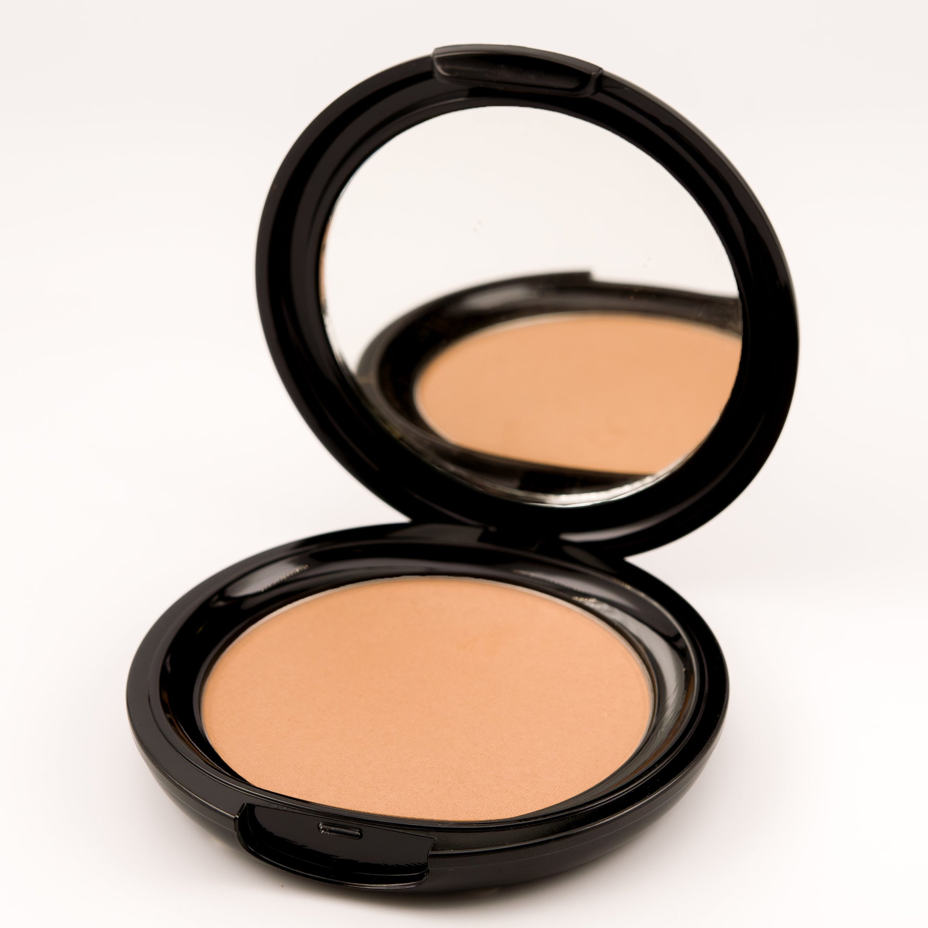 Compact powder in an open black case on a white background